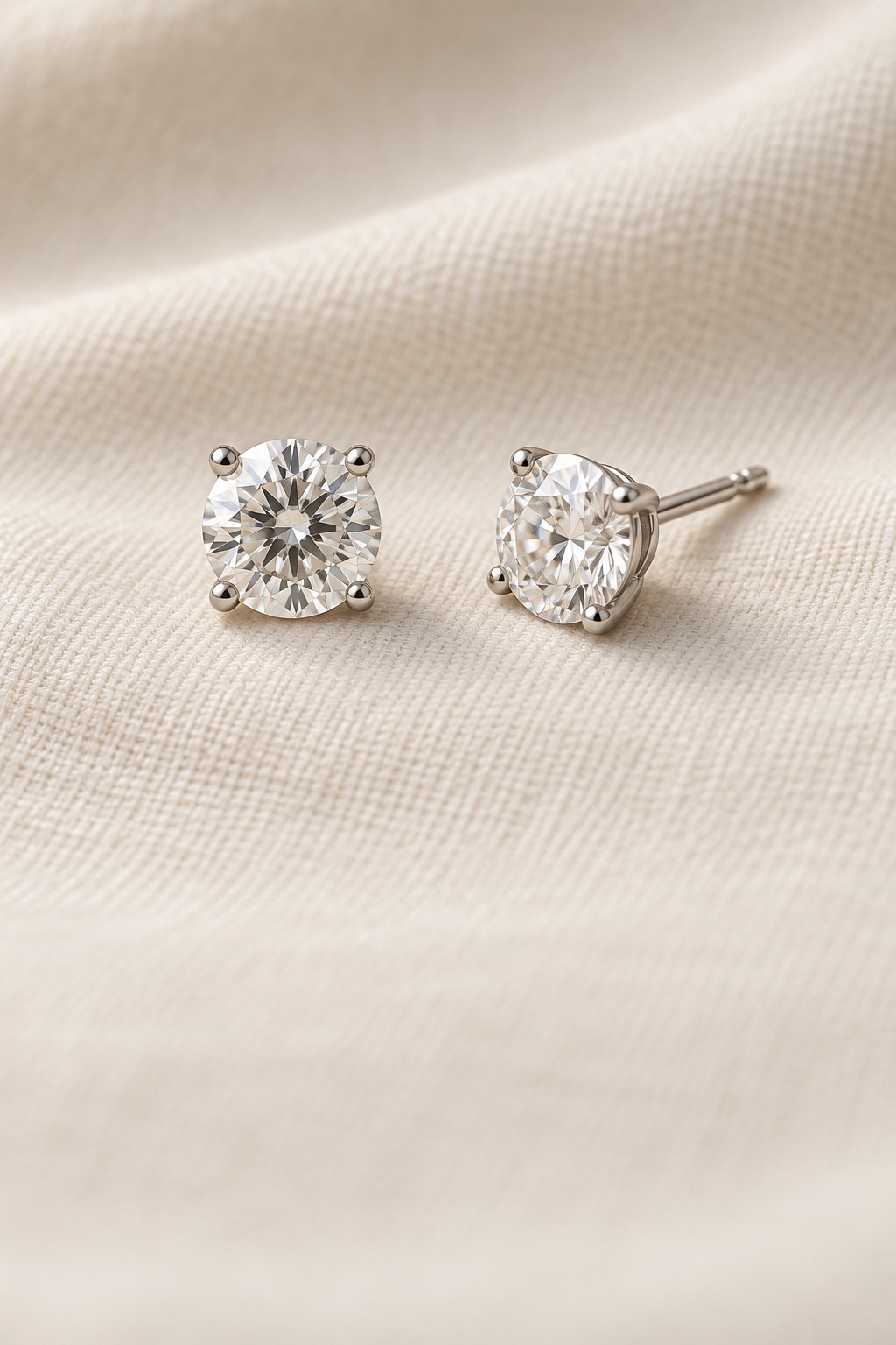 Round diamond stud earrings on ivory linen