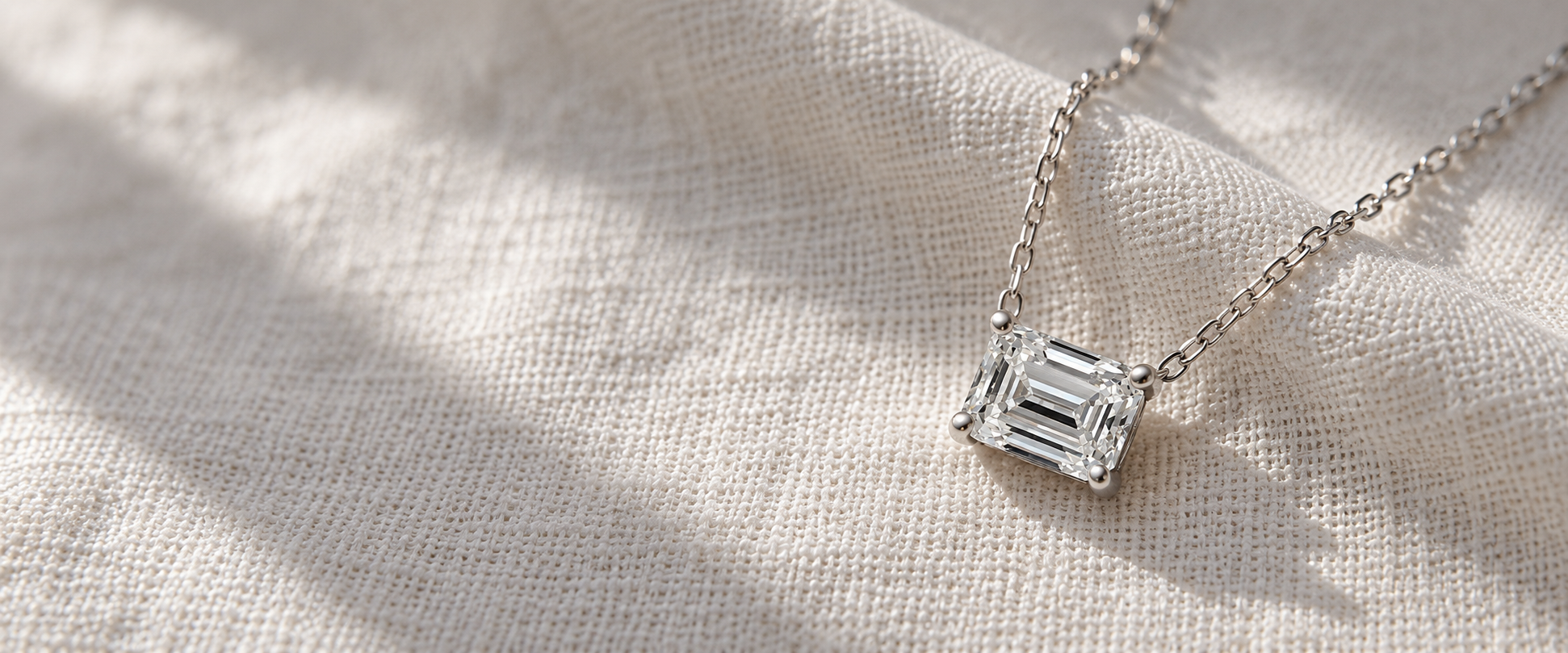 A single emerald-cut diamond pendant on ivory linen